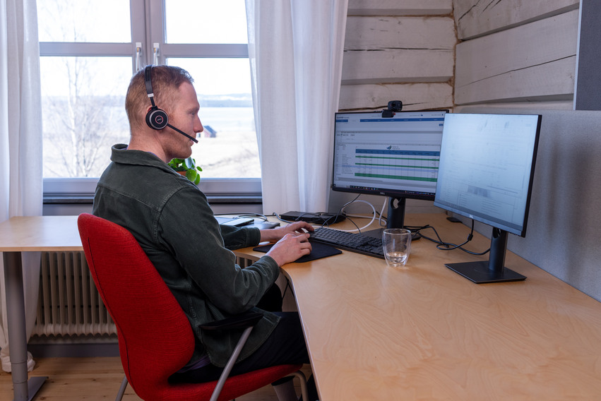 Person som sitter vid ett skrivbord och pratar i telefon