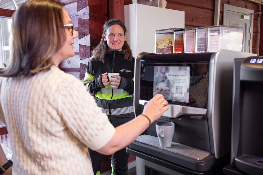 Två anställda som pratar vid kaffemaskin